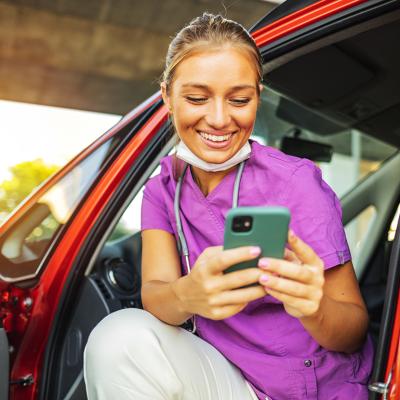 A happy travel nurse taking a break in her car.