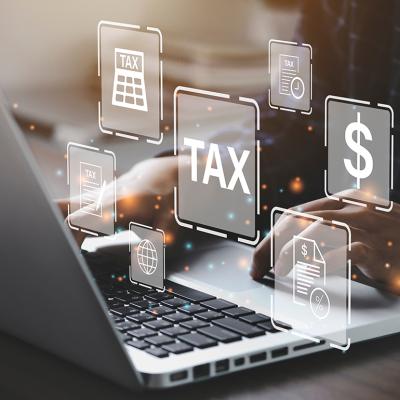 Businessperson using a laptop and holographic concepts of tax are illustrated.