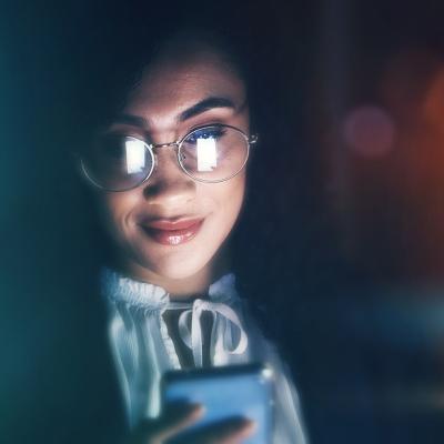 A female employee using a phone at night.