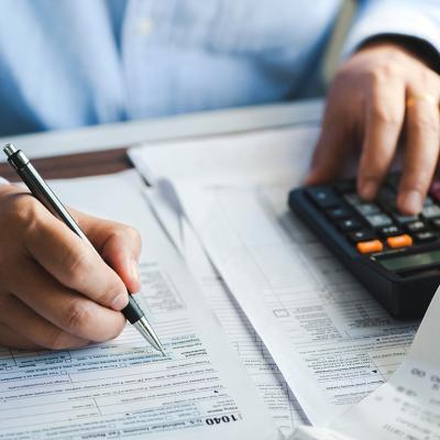Businessperson calculating taxes and filling out a tax form.