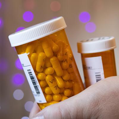 Person holding two bottles of prescription medicines.