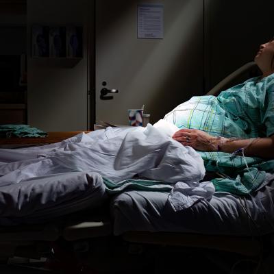 A pregnant woman in labor laying in a maternity ward bed with rays of sunlight on belly stomach.