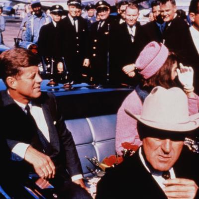 Texas Governor John Connally adjusts his tie as President John F. Kennedy and First Lady Jacqueline Kennedy settle into the rear seats of their car before the Dallas motorcade on November 22, 1963.