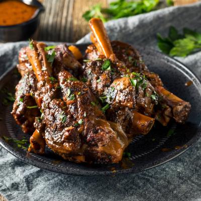 Homemade braised lamb shanks with sauce and herbs.