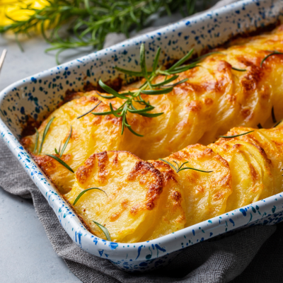 Potato gratin topped with rosemary in a baking dish