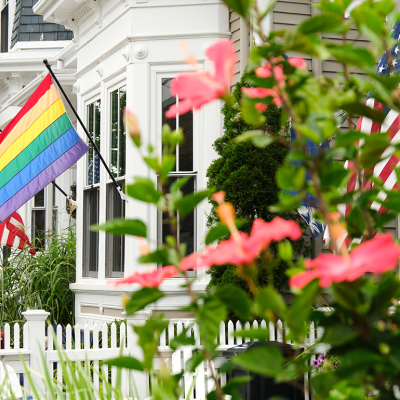A rainbow pride flag and American flags affixed to a home.