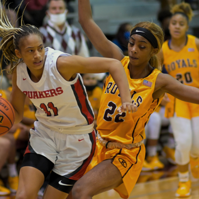 Two basketball players on a basketball court during girls basketball tournament. 