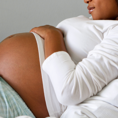 A pregnant person lying in a hospital bed cradling her stomach.