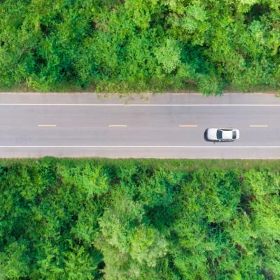 An aerial view of a car driving through a forested area.
