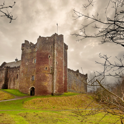 A castle made of gray stone with a number of towers, the tallest of which is in the center of the castle. 