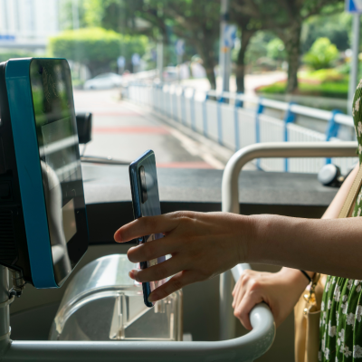 A person uses contactless payment on their smartphone to pay for their bus fare as they board.