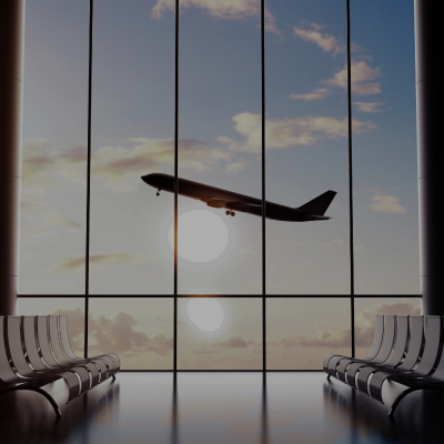 An airport terminal building with rows of empty chairs and airplane seen through the windows.