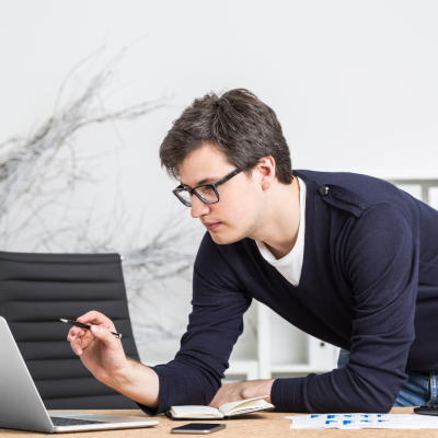 A man leaning on a desk and looking into computer.