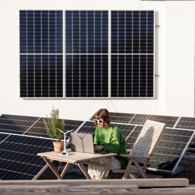 A woman working on a laptop on a rooftop covered in solar panels.