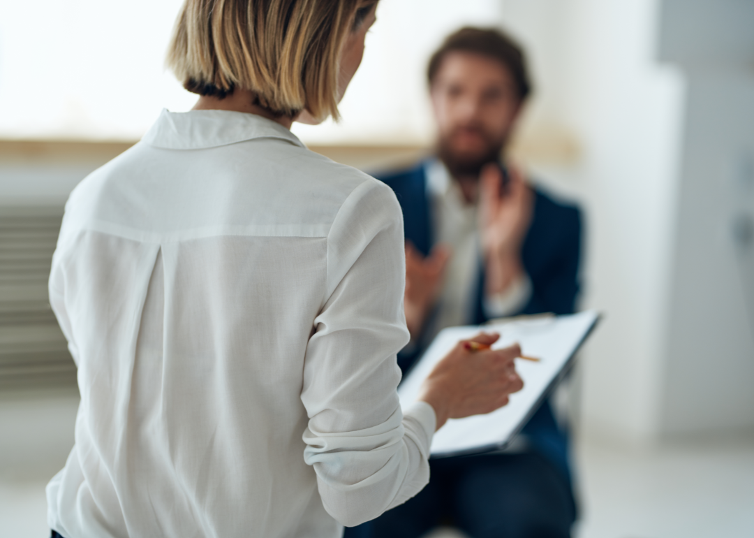 A therapist listening to a client who is seated on the couch.