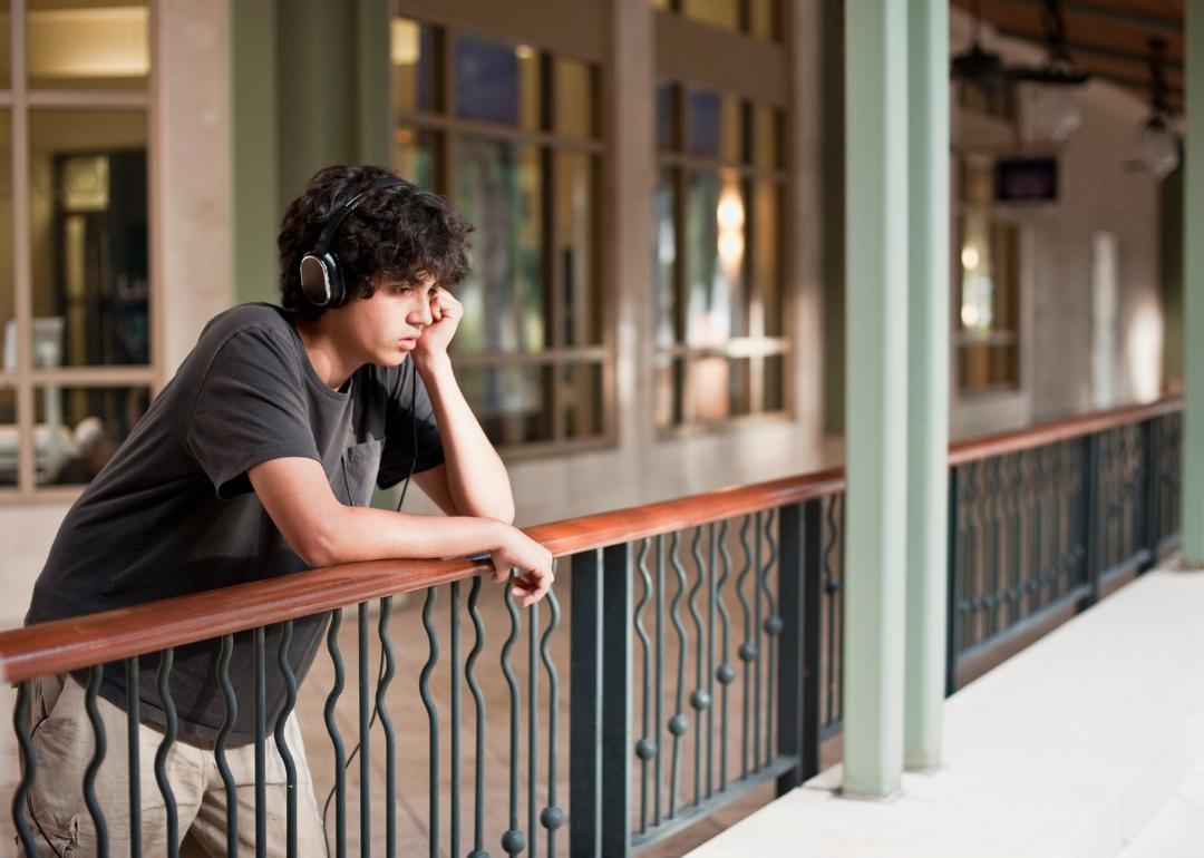 A teenage boy listening to music with a sad look on his face.
