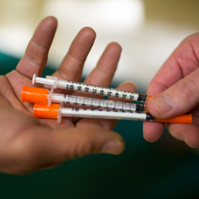 One person handing another three syringes at Howard Center's needle exchange program in Burlington, Vermont