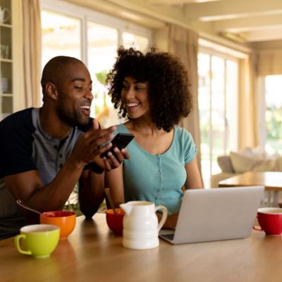 A couple on a cellphone in the kitchen.