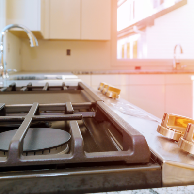 Close-up of gas range with pink and yellow light coming in the kitchen window.
