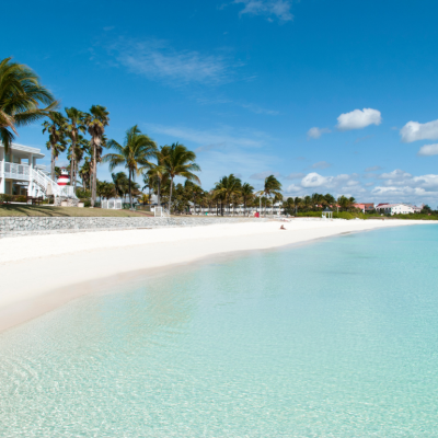 Homes on white sandy beach with crystal clear water.