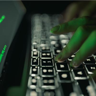Fingers on a computer keyboard with dark background.