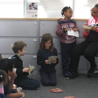 Kids sit and learn about money at a bank.