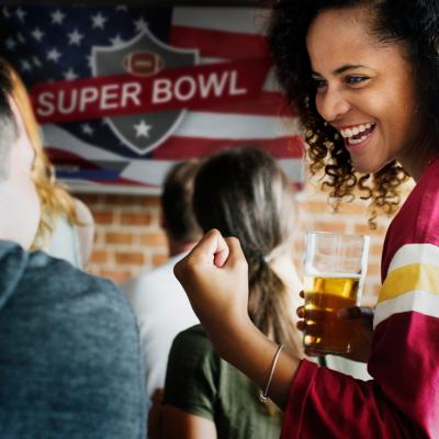 People cheering with Super Bowl banner in background.