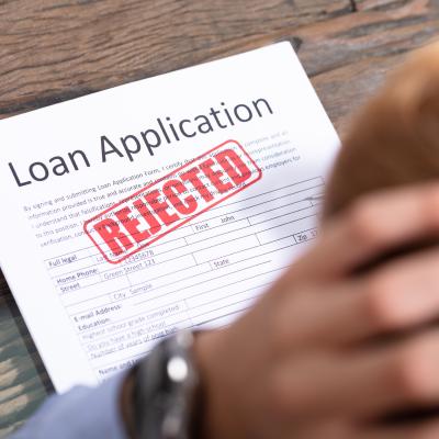 Stressed person looking at a rejected loan application.