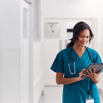 Female doctor in scrubs in hospital using a digital tablet.