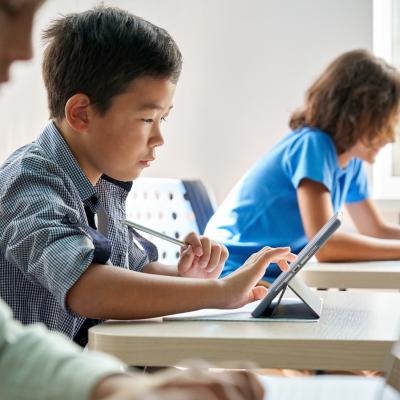 Elementary-aged students using digital tablets in classroom.