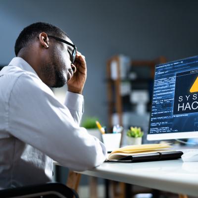Person looking distraught at system-hacked notification on a computer.