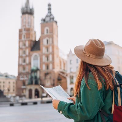 Tourist holding a paper map, looking out onto a city square.