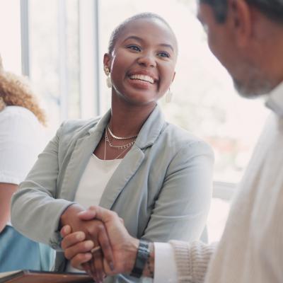 Man and woman shaking hands while sitting.