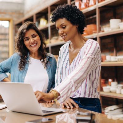 Two women ceramists using a laptop while working together.