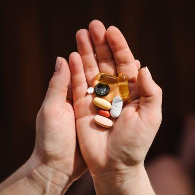 Hands hold supplements on blurred background.