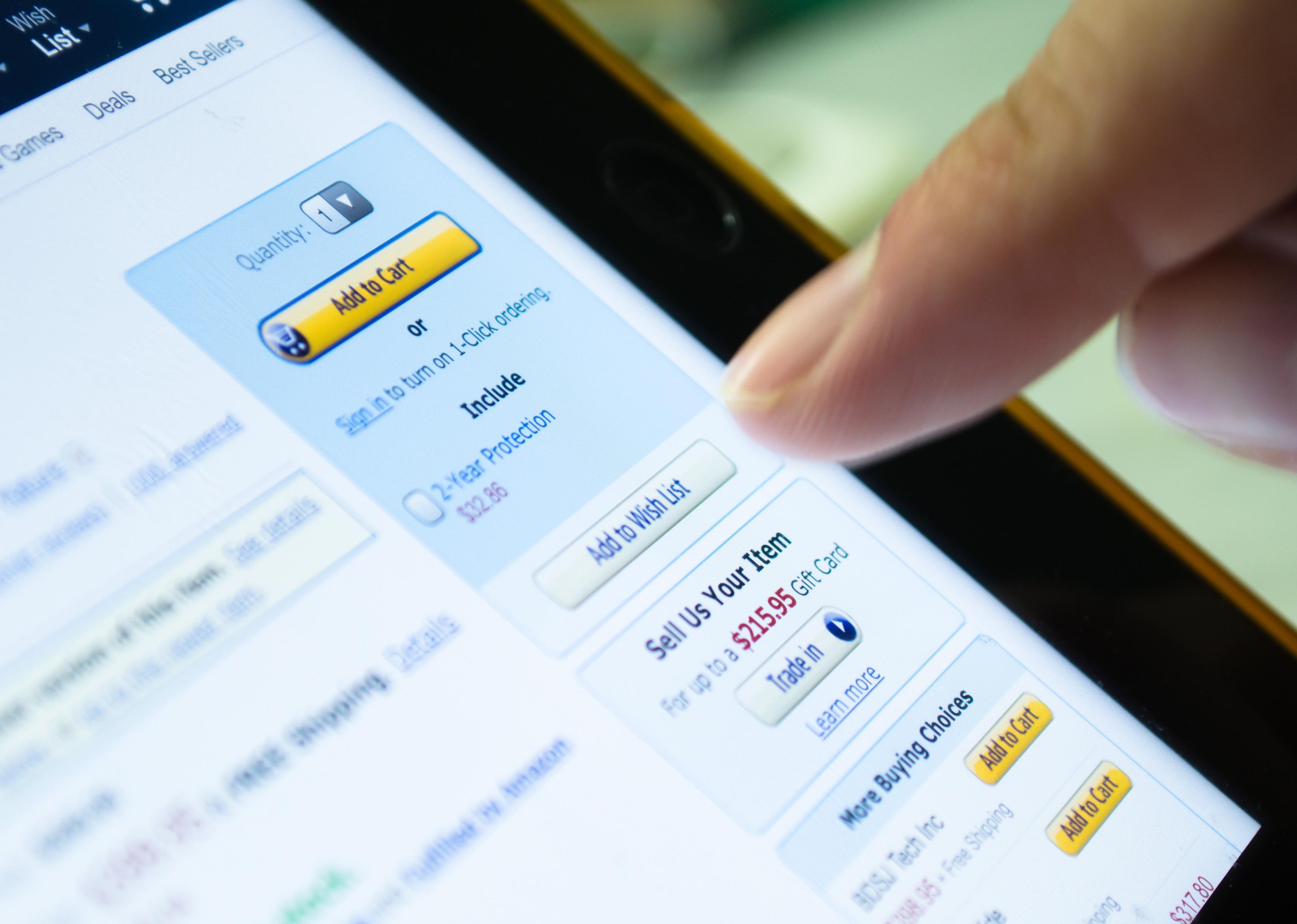 Unidentified finger touches screen of tablet device on 'Add to Wish List' button in Amazon.