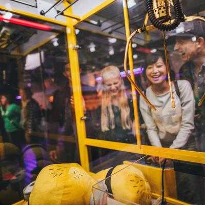 Group of friends playing with a claw machine.