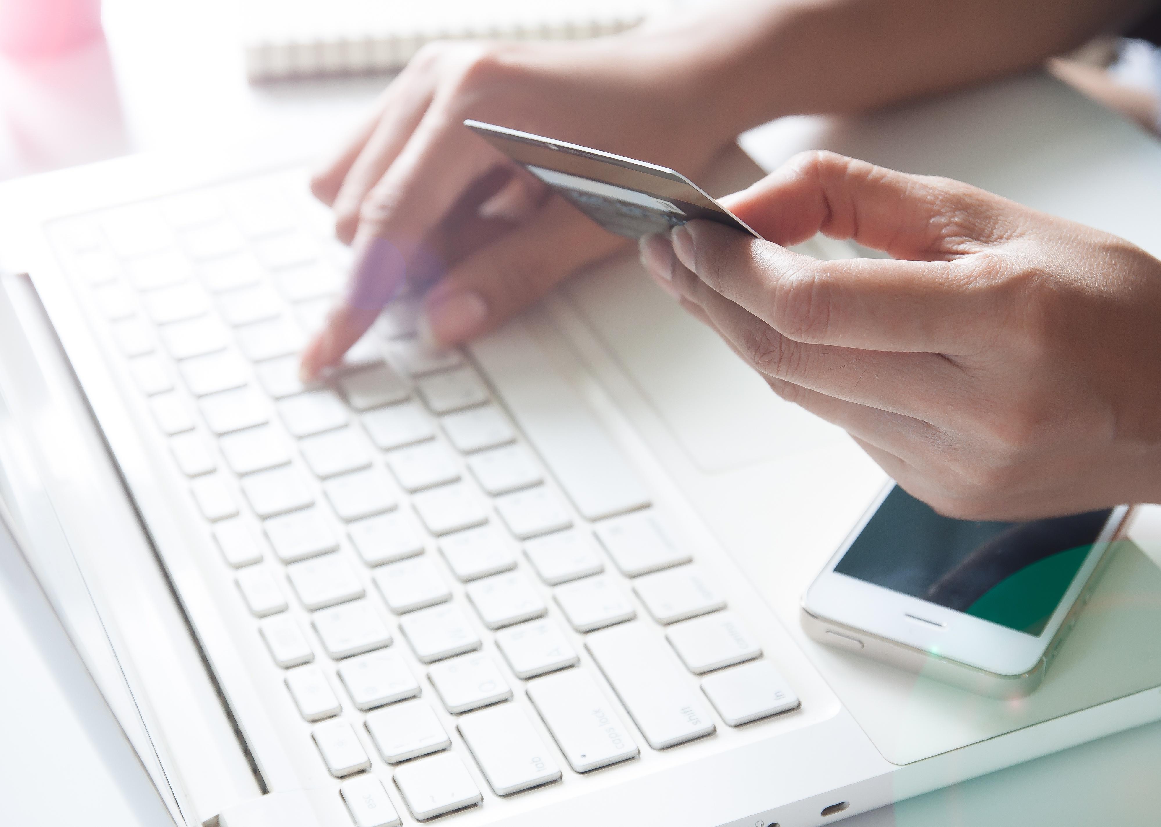 Hand holding credit card and using laptop