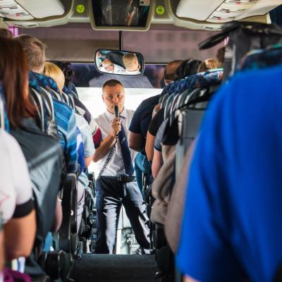 Tourists and a male tour guide with a microphone in the bus