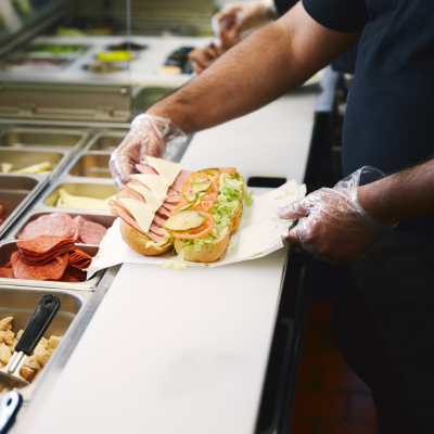 A fast food worker assembling a sandwich