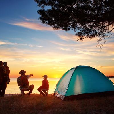 Family of four set up camp near the lake and watching the sunset.