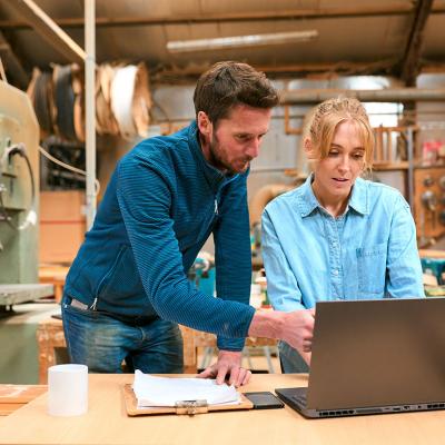A pair of woodwork business owners reviewing reports in a laptop.