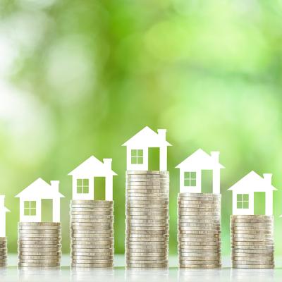 Tiny figures of residential houses atop coin stacks.
