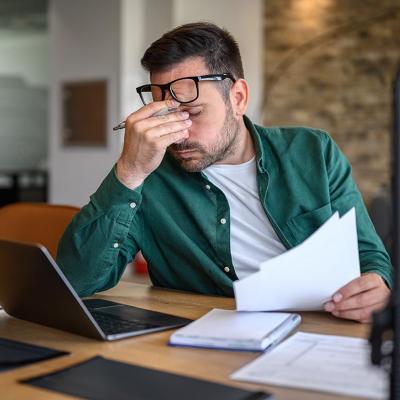 Anxious landlord rubbing eyes while looking at documents.