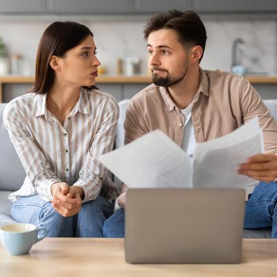 Young couple looking at each other with a serious expression while going through financial documents.