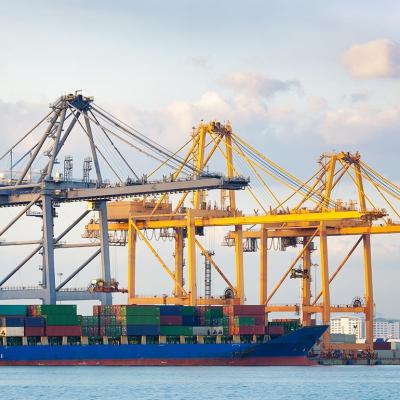 Two yellow and one gray crane with a cargo ship in a port.
