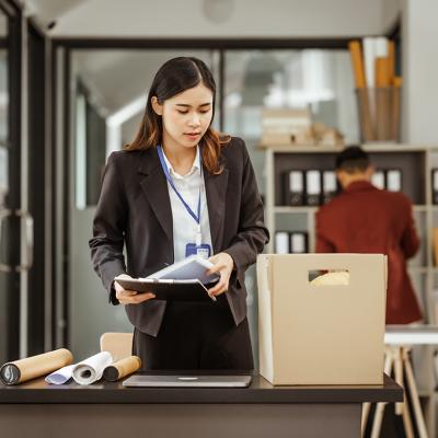 Young businesswoman preparing her work items to put in a box after being laid off.