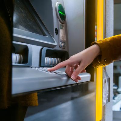 A woman entering info in an ATM to withdraw money.