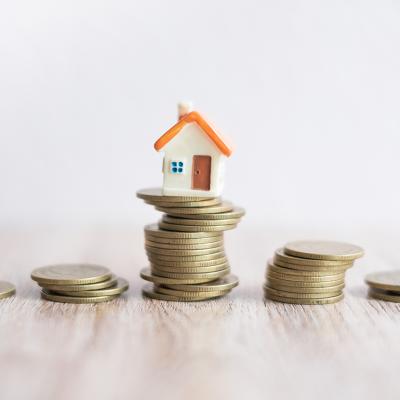 A miniature house on top of a stack of coins.