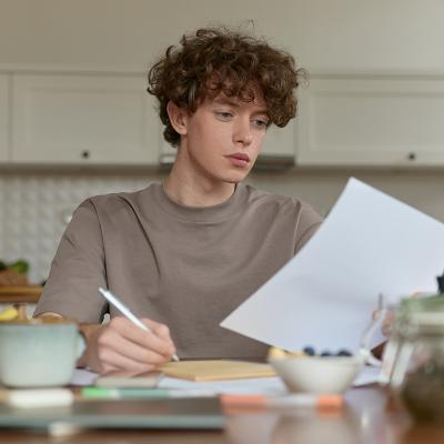 A young man reviewing a document during breakfast.
